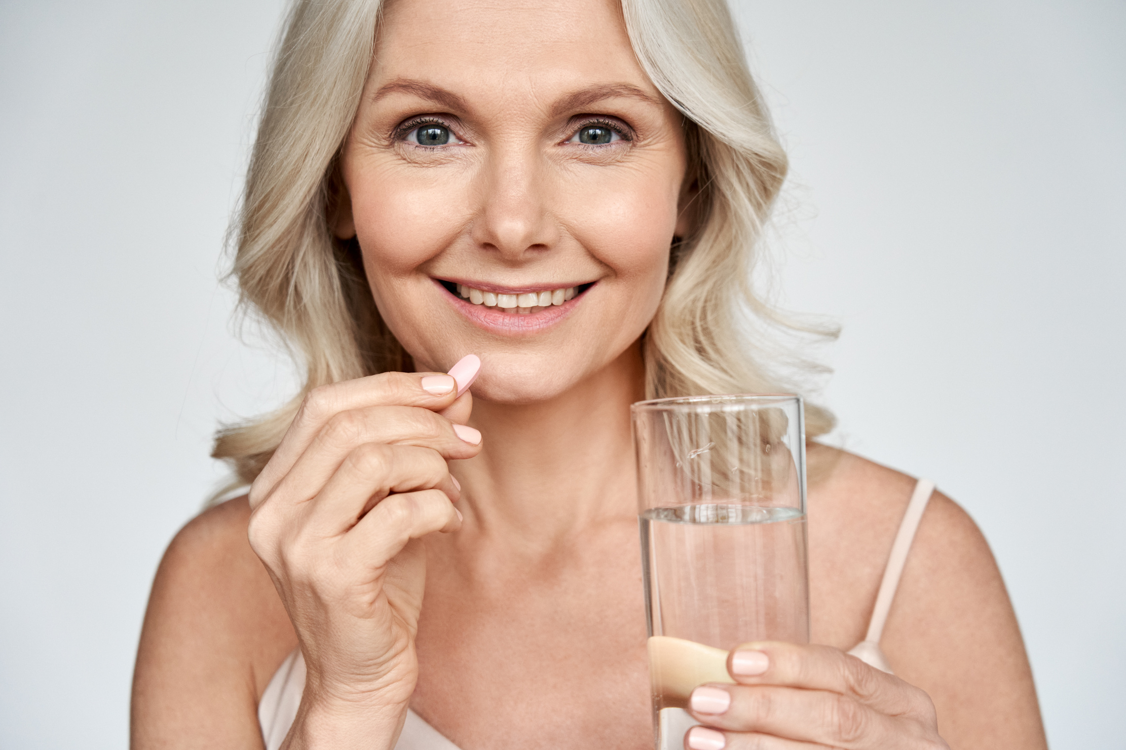 Smiling Middle Aged Woman Taking Supplement Pill